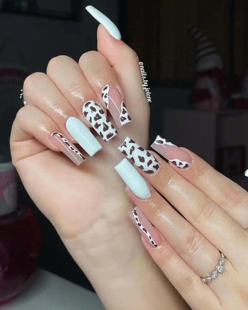 White and brown acrylic nails with cow print nail design. 