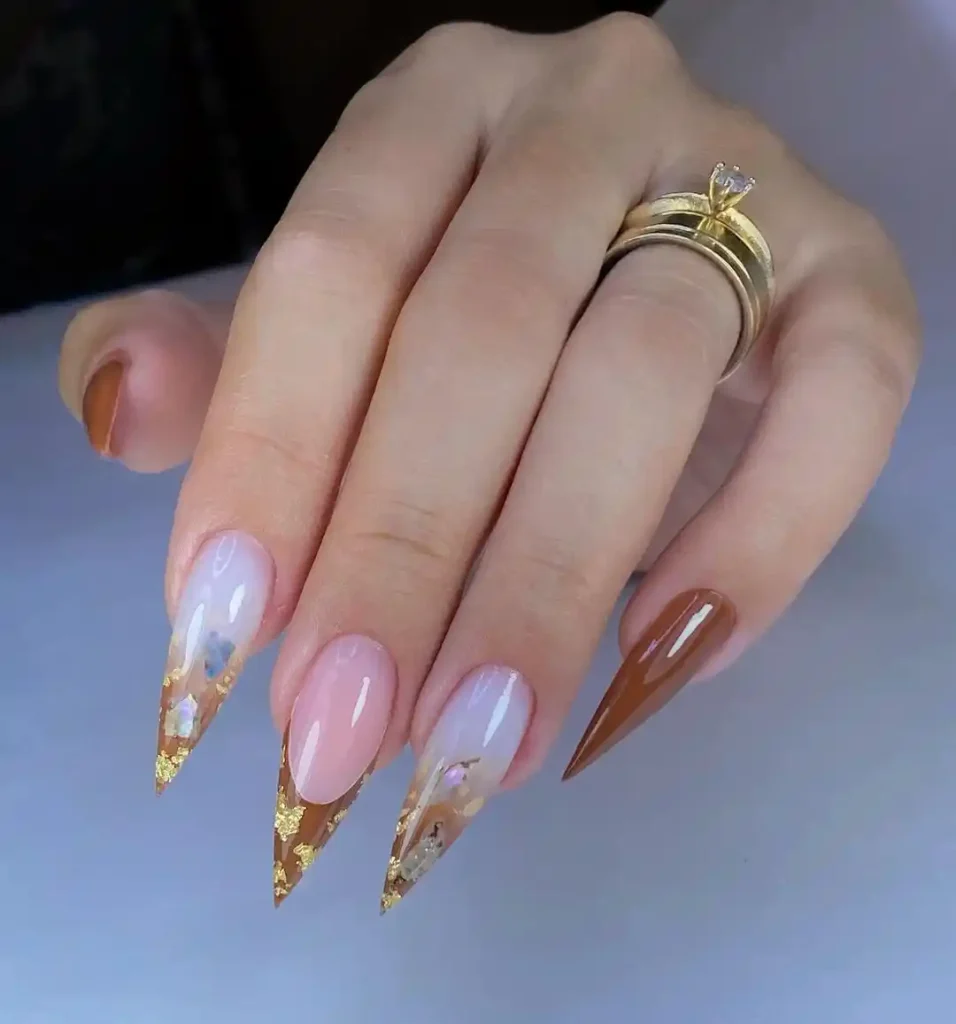 Pointed stiletto nail shape with brown ombre, French tips, and gold foil art. 