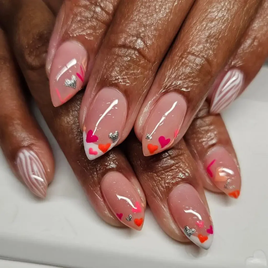 Nude arrowhead nails with bright heart tips and wavy patterns. 