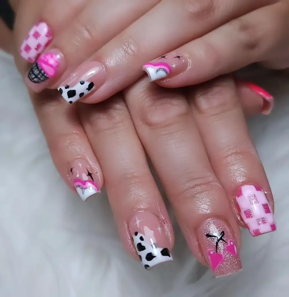 Pink glitter nails with cow print and cherry nail designs. 