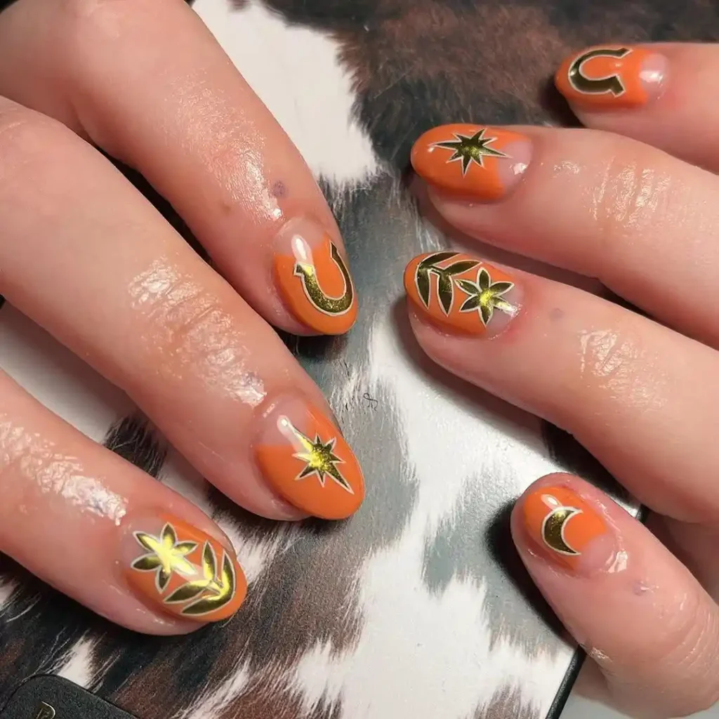 Short orange nails with a half-moon design and gold retro stickers.