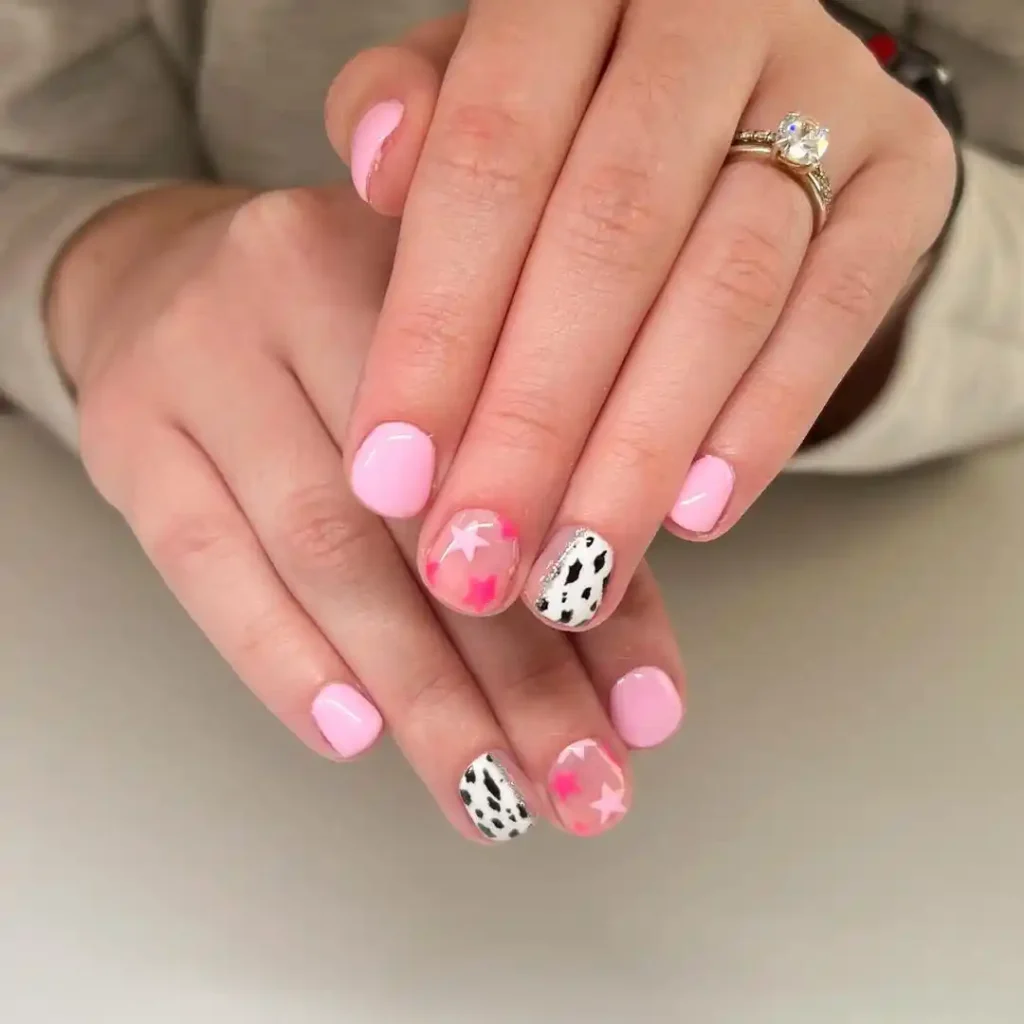 Cute cow print and star patterns on short pink nails. 