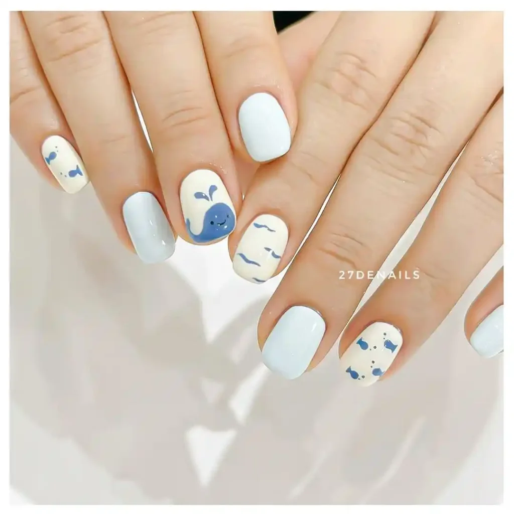 Summer beach nails with cute whale designs and blue and white nail colors.