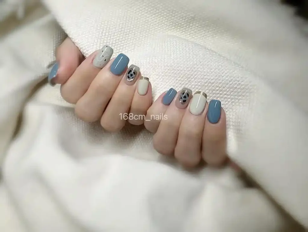 Short squoval nails with blue and white nail art. 