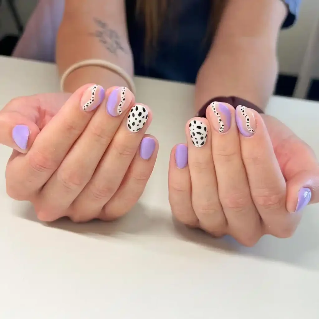 Matte purple manicure on short nails with cow print and swirl nail art. 