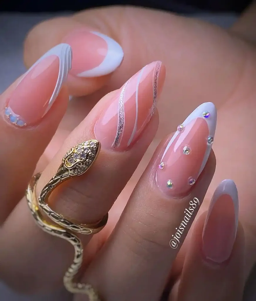 White almond nail art with French tips, swirl art, and crystals.