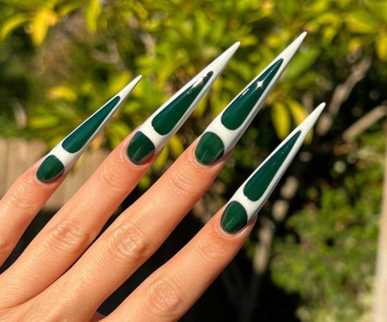 Long acrylic stiletto nails with white and green nail art. 