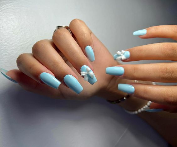 Cute baby blue nails with coffin nail shapes and 3D coquette bows. 