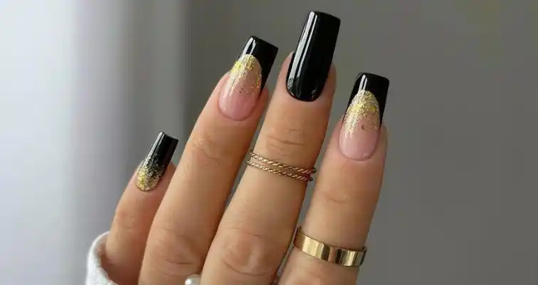 Shiny black square nails with French tips and gold glitter art. 