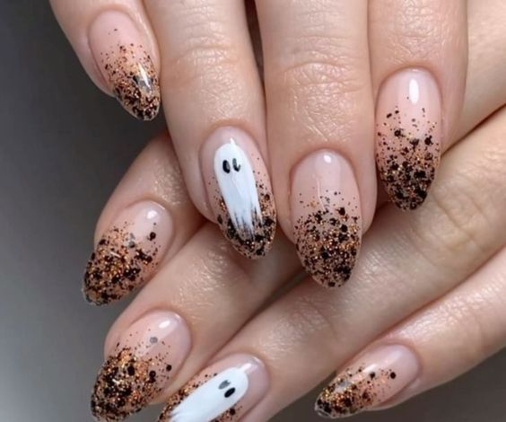 Black and gold glitter ombre tips with ghost designs for Halloween. 