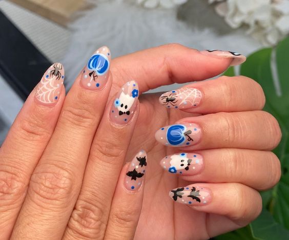 Blue Halloween nail art with pumpkins, bats, and mushrooms. 