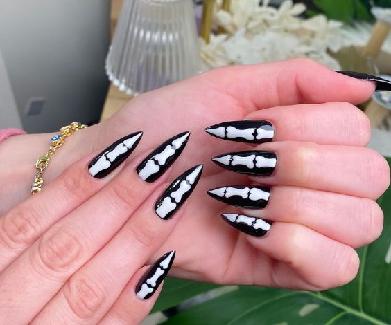 Bones nail art on black pointed stiletto nails. 