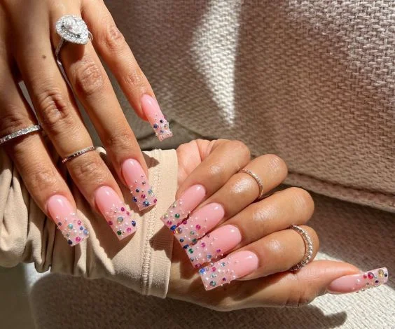 Cute birthday nails with nude pink nail base and colorful studs.