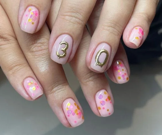 Birthday balloons and confetti nail art on pink nails.