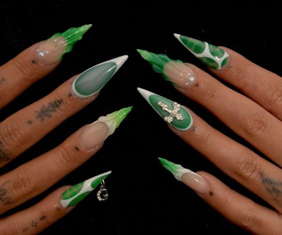 Green and white stiletto nails with 3D art and nail piercing. 
