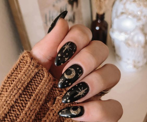 Black nails with gold glitter and moon nail art. 