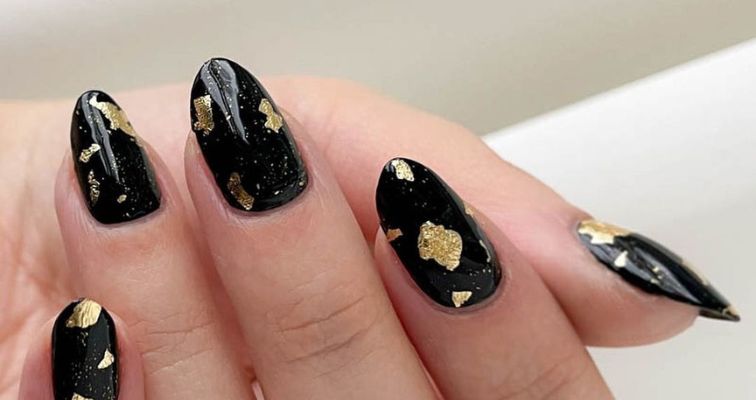 New Year's nails with black nail color and gold foil art.