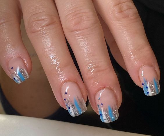 Short squoval nails with light blue and glitter abstract art.