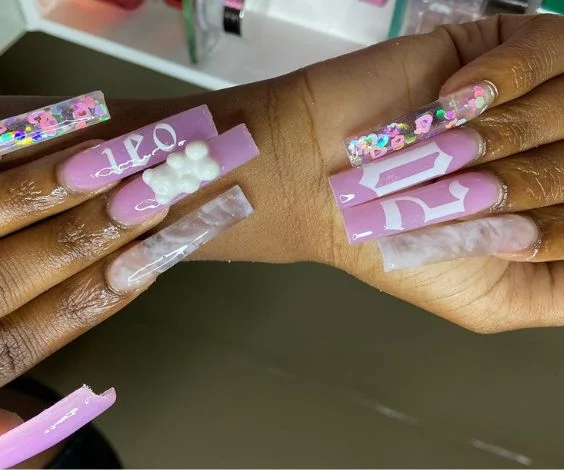 Long pink and white acrylic nails with zodiac birthday manicure.