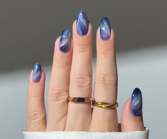 Oval nails with blue and white marble nail art.