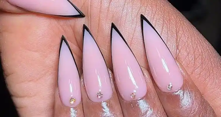 Nude acrylic nails with sharp almond tips and black French manicure. 
