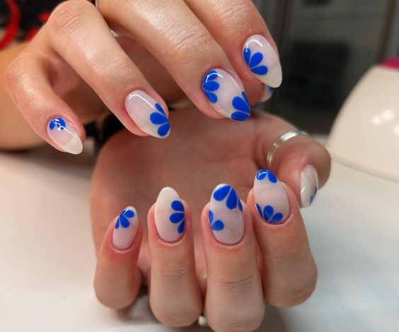 Royal blue flower designs on short almond nails.