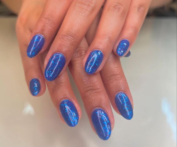 Oval nails with royal blue glitter nail polish. 