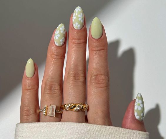 Sage green almond nails with white flower nail art.