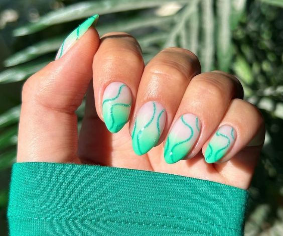 Cute ombre nails with mint green nail color and glitter swirls. 