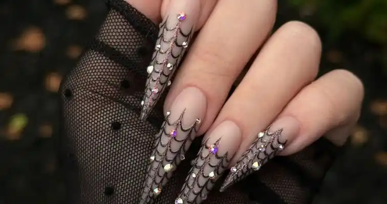 Long acrylic stiletto nails with black spider web nail art and crystals.