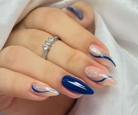 Blue and white almond nails with glitter swirl designs.